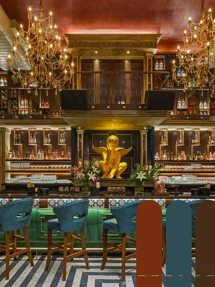 The grand, multi-level bar at Suzy Q is designed for impact. Ornate chandeliers, a mezzanine level, and a bold color palette of teal, gold, and brick red create a maximalist and energetic atmosphere.