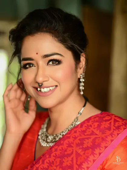 A happy, smiling close-up of actress Sohini Sarkar. Her genuine smile and the vibrant red of her saree create a warm and inviting portrait for Sangbad Pratidin.