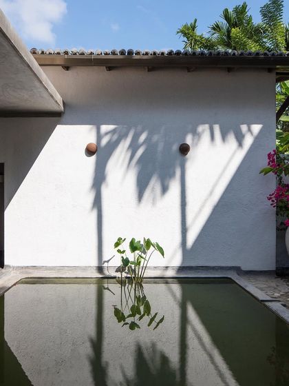 The main villa's courtyard and lily pond, where the play of light and shadow on the white walls creates a serene and contemplative atmosphere.