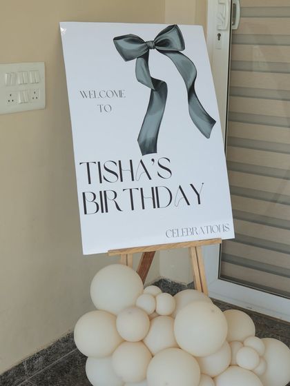 The full view of the welcome easel for a 35th birthday, with a small cluster of white balloons at the base. It’s a simple touch that connects the entrance decor with the main party area.
