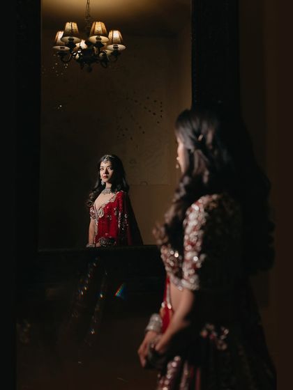 A creative mirror portrait of Sanjali. This shot plays with reflections and perspective to create a thoughtful and artistic image, capturing the bride in a moment of quiet contemplation.