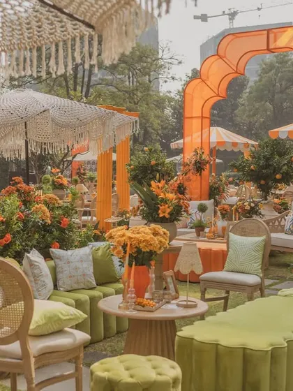 A comfortable lounge area at the 'Orange Orchard' Haldi, with a mix of green and orange velvet seating and custom-printed cushions.