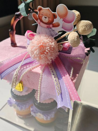 The top of this acrylic bag hamper is a work of art itself. A plush velvet lid is adorned with a multi-layered bow, pom-poms, and a cute teddy bear cutout, making it an adorable keepsake.