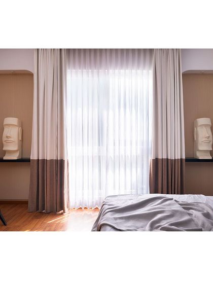 The niches flanking the window serve as perfect display areas for the client's sculptures. The two-toned curtains add another layer of custom detail to this art-filled bedroom.