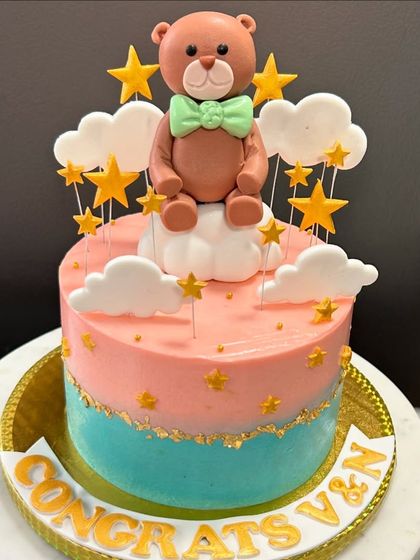 A sweet teddy bear-themed cake to celebrate a baby shower. The pink and blue design with a cute bear topper is perfect for welcoming a new arrival.