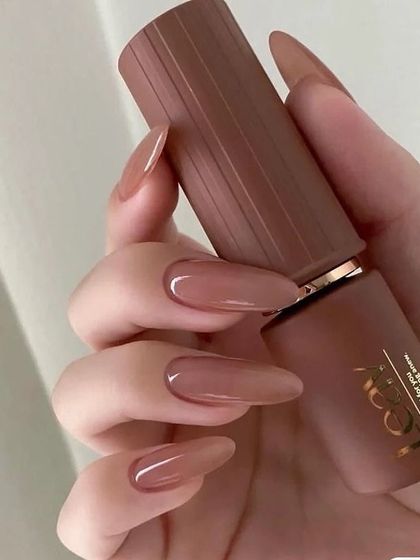 A glossy, jelly-like brown polish on long almond nails. This color is rich, warm, and super trendy.