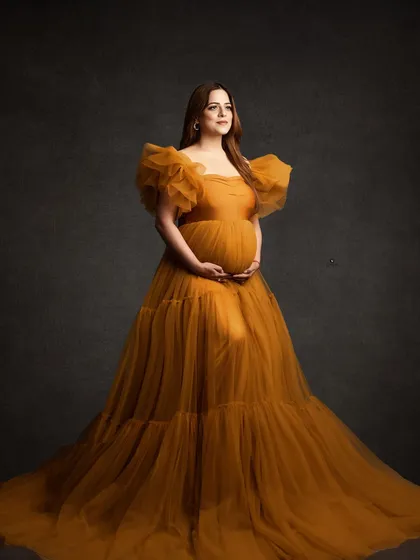 A classic portrait in a beautiful mustard-colored tulle gown. The simple, dark grey background allows the rich color and texture of the dress to take center stage.