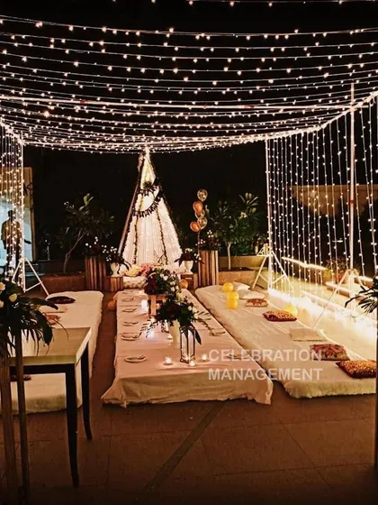 I can turn any terrace into a magical setting for a birthday dinner. This setup features a canopy of fairy lights creating a starry sky effect, with low seating on mattresses and cushions for a cozy, intimate gathering with friends and family.