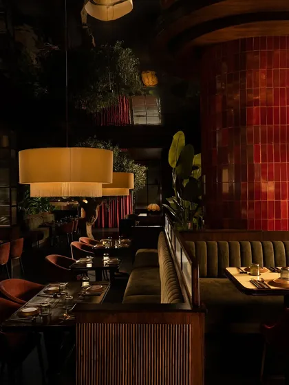 The interplay of textures and reflections. A column of glossy red ceramic tiles punctuates the space, while the mirrored ceiling and fluted wood panels add layers of visual complexity.