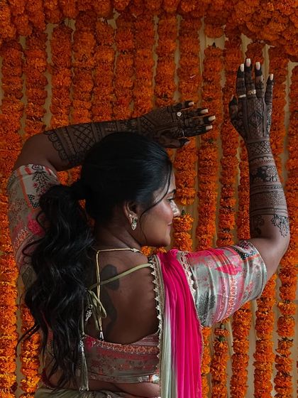 A graceful dance pose by Tejashree, showing the back of her mehendi-adorned arms.