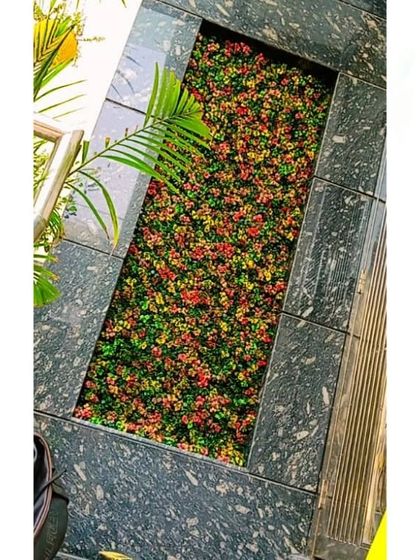 A top-down view of the colorful artificial flower bed set within a black marble frame.