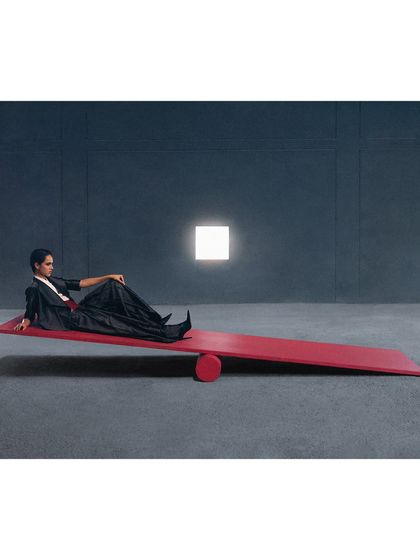 A conceptual shot featuring a red seesaw. This image for Payal Khandwala plays with the ideas of balance, color, and minimalism in a stark, architectural space.