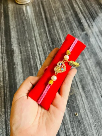 This evil eye heart charm bracelet is paired with a feather charm, creating a bohemian and stylish look.