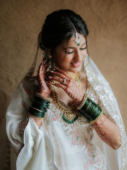 Adjusting her bangles, this shot highlights her beautiful henna and the emerald green details in her jewelry.