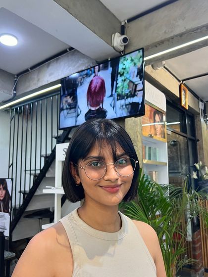 The final result: a happy client with a stylish short bob and bangs that perfectly suit her features.