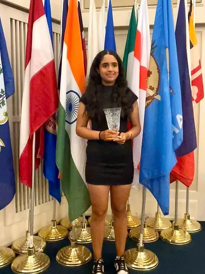 Mahreen Bhatia stands proudly with her trophy and the flags of competing nations after finishing 4th at the US Kids World Teen Championships in Pinehurst, USA.
