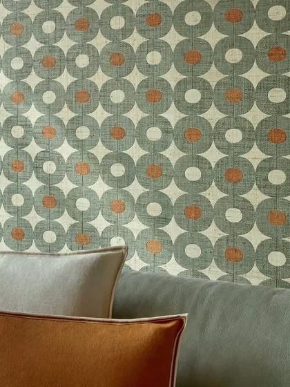 A close-up of a graphic wallpaper from Élitis, woven from raffia to create a bold, textured pattern of interlocking circles. This design celebrates artisanal materials and transforms the wall into a vibrant, tactile work of art.