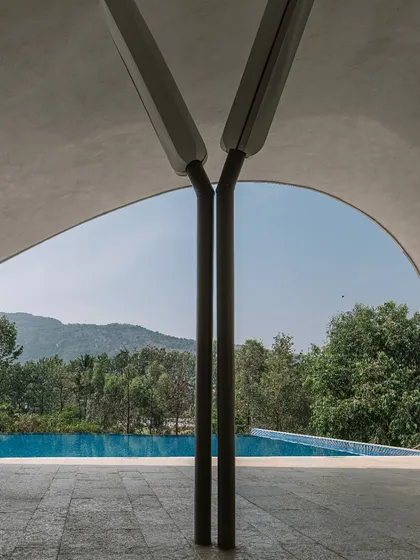 A detail shot focusing on the custom Y-shaped columns that support the sweeping roof of the Aqua project, framing a perfect view of the sky and hills.
