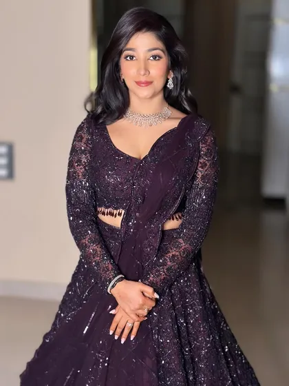 Sanjana's reception look. The deep purple outfit is complemented by a soft, glowing makeup look that enhances her features.