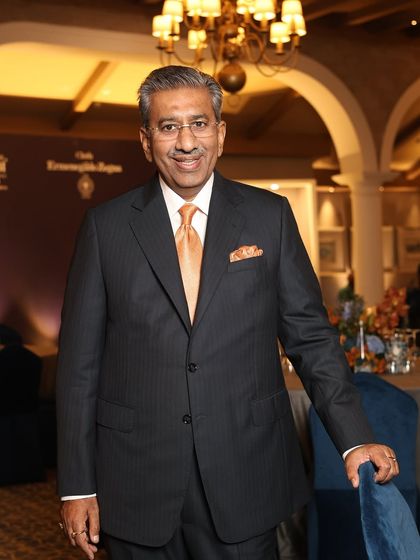 Our founder, exuding timeless elegance in a pinstripe suit with a contrasting orange tie and pocket square, at the Ermenegildo Zegna event he proudly hosted.