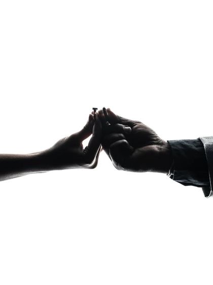 A minimalist and symbolic silhouette of the couple's hands coming together. This artistic shot focuses on the simple gesture of connection, representing the start of their journey.