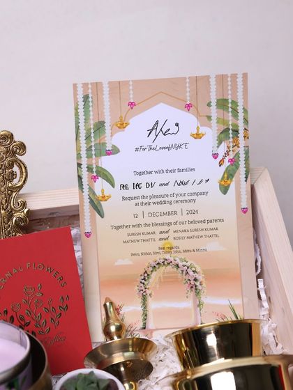 The beautifully designed wedding invitation card, which sets the theme for the entire gift box with its elegant fonts and cultural motifs.