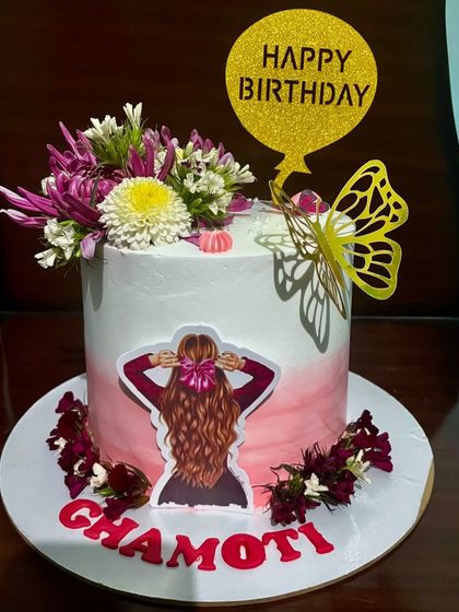 This cake features a beautiful silhouette illustration, fresh flowers, and a golden butterfly. The pink ombre frosting adds a soft, feminine touch to this artistic and personalized birthday cake.