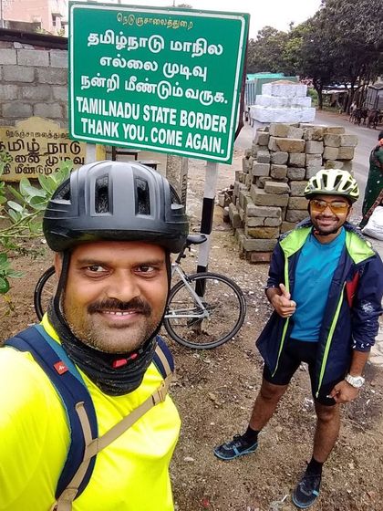 Two riders celebrating at the Tamil Nadu border sign. Crossing state lines on a bicycle is an incredible feeling.