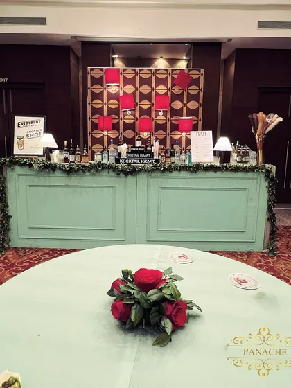 The after-party bar, designed in a cool sage green to contrast with the red decor. The backdrop from the lounge area continues behind the bar for a cohesive look.