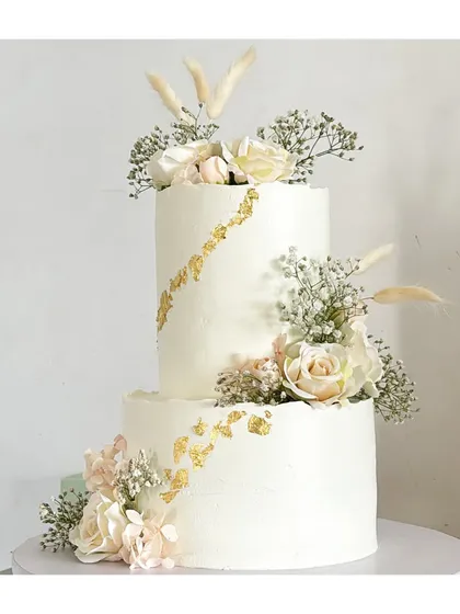 This timeless two-tier cake, adorned with delicate florals and a touch of gold leaf, is the perfect centerpiece for an elegant engagement or wedding celebration. It’s crafted with love and is completely eggless and free of fondant.