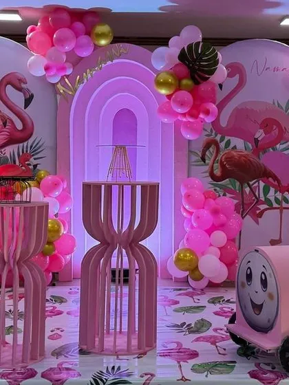 A stunning flamingo-themed party, bathed in pink light. The setup includes multiple flamingo props, a pink toy train, and lush balloon arrangements.