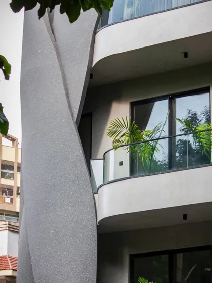 A view of the Lotus Villa's twisting concrete form, showcasing its raw and intentional design. The sculptural element is framed by surrounding trees, highlighting its organic inspiration.