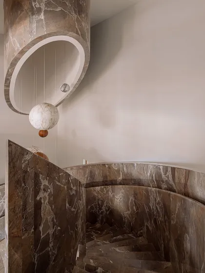 We transformed this stairwell into a surreal experience with a 'confetti carnival' installation. Oversized spheres of wood and marble are suspended by cables, and they light up in the evening to create a magical journey between floors.
