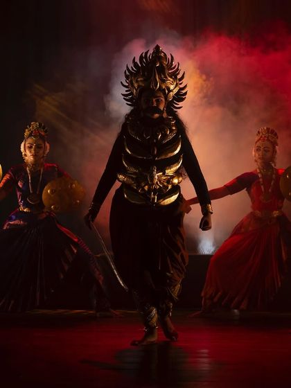 The villainous Kamsa in a powerful stance, surrounded by his guards. The red and gold lighting combined with the performers' intense expressions create a truly menacing atmosphere.