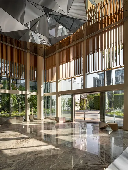 The ground floor reception for directors features a faceted stainless-steel ceiling sculpture and custom seating, continuing the architectural language of the exterior into the interior spaces.