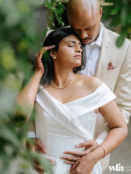 An intimate embrace, framed by greenery, this photo feels private and deeply romantic.