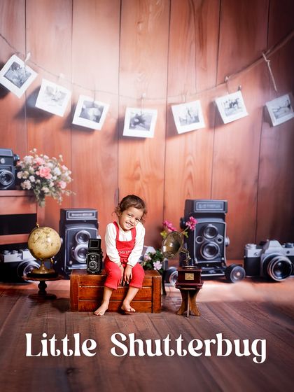 A little shutterbug in the making. This setup, complete with a photo garland and classic cameras, creates a nostalgic and creative atmosphere for a unique photoshoot.