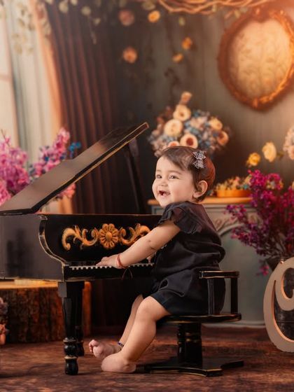A beautifully lit, classic portrait of a little girl at her piano, set against a romantic, vintage-inspired backdrop.