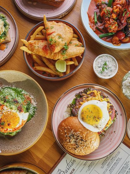 A brunch spread featuring a variety of savory dishes. This flatlay shows off the breadth of a menu, from fish and chips to burgers and egg dishes, inviting customers to come in for a feast.