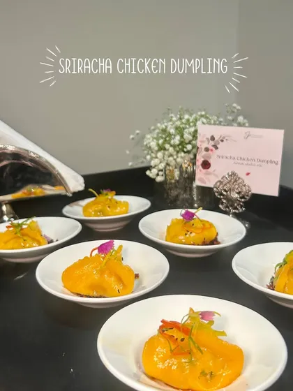 Sriracha Chicken Dumplings, plated individually and garnished with edible flowers, adding a touch of spice and beauty to the event.