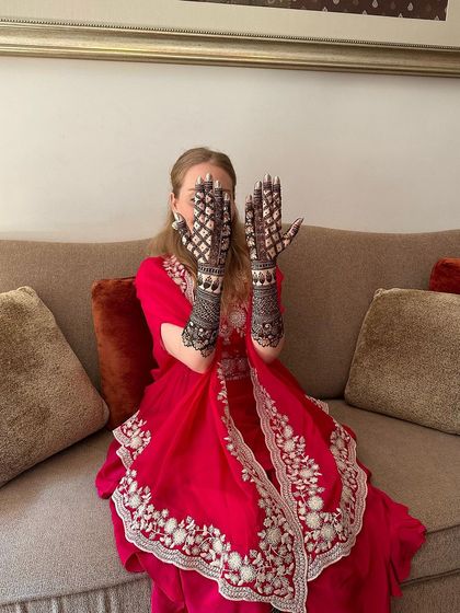 A playful pose from the bride, showing off her intricate jaali-work mehndi.