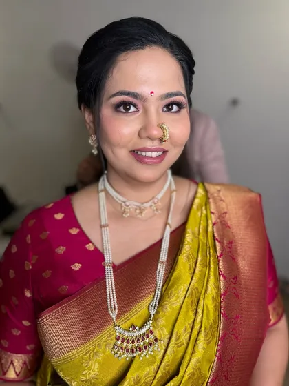 A smiling portrait of the bride, showing her complete look with traditional pearl jewelry.