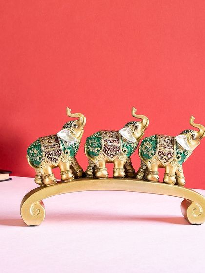 This showpiece features a trio of elephants in a row, decorated with intricate green and gold patterns. It's a beautiful representation of family and unity, perfect for a console table.
