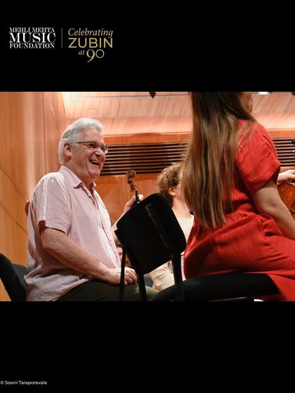A candid moment of joy and camaraderie during rehearsals with Pinchas Zukerman. The 'Celebrating Zubin at 90' concerts were not just about performance but also about the deep friendships forged through music over many decades.