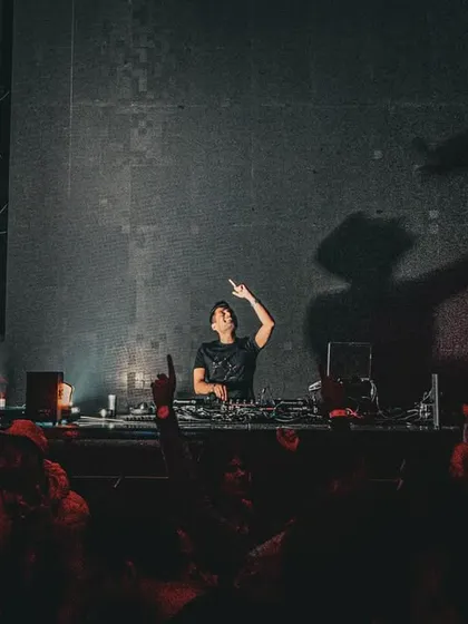 A silhouette against the stage lights at Liit, Pune, with the crowd's hands reaching up.