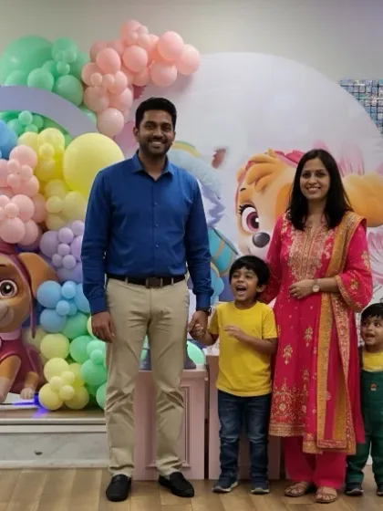 The happy family posing in front of the Paw Patrol stage. The setup included a sequin backdrop, character cutouts, and a lighted number '3'.
