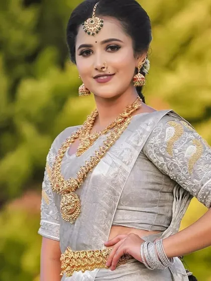 A beautiful look in a silver Kanjeevaram saree, paired with traditional gold temple jewellery. The makeup is soft and enhances the model's features.