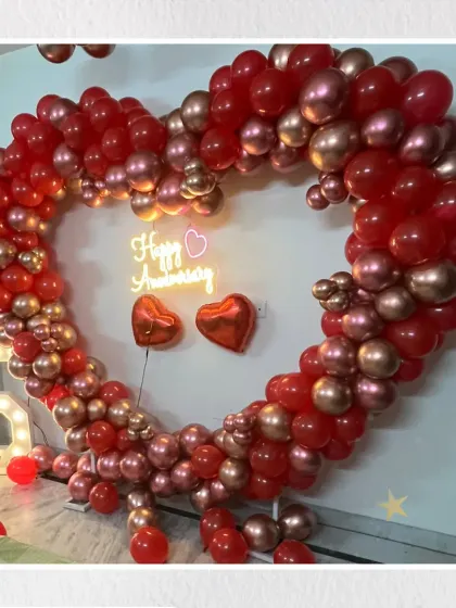 Celebrating a love that lasts a lifetime. This grand heart-shaped balloon arch, made with rich red and shimmering rose gold balloons, creates the perfect romantic photo opportunity for a very special anniversary.