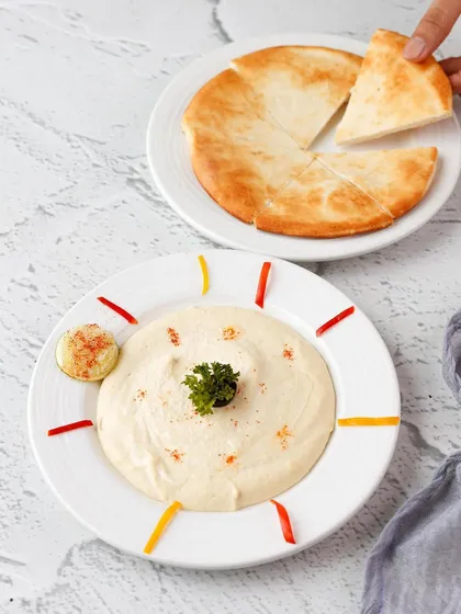 A simple and clean shot of creamy hummus and fresh pita bread for a Mediterranean restaurant menu.