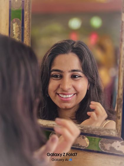 A creative portrait using a mirror to capture a reflection. Her genuine smile and the colorful, blurry background create a warm and intimate feel.